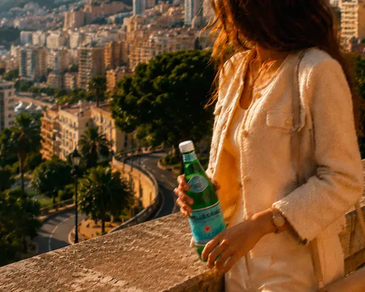 A woman holding a bottle of S.Pellegrino on a balcony in Monte Carlo.