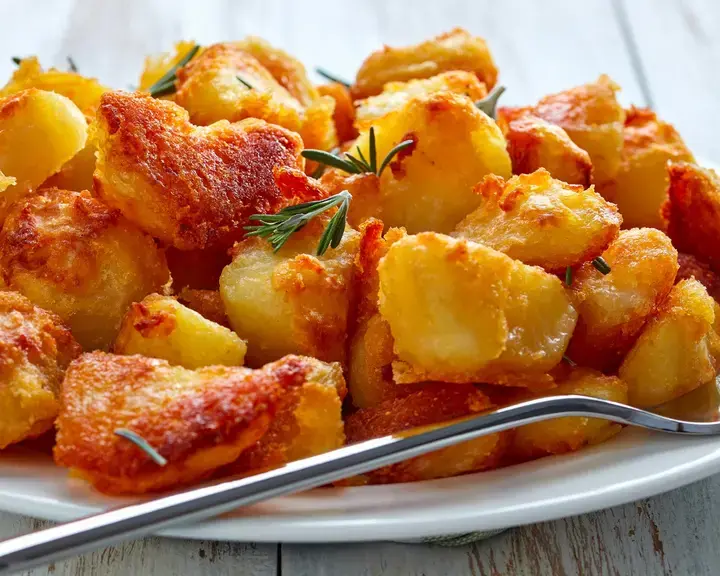 Crispy roast potatoes on a plate with a fork.