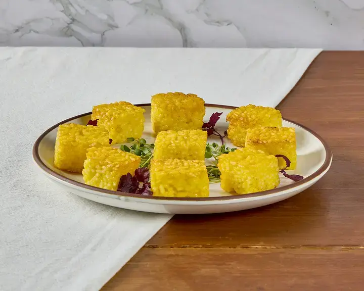 Yellow risotto al sato bites on a plate.