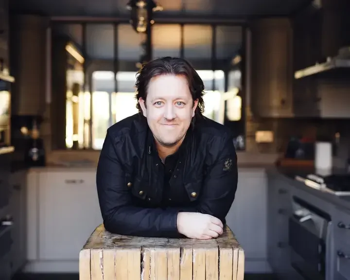 Chef Ashley Palmer-Watts leaning on a butcher's block.