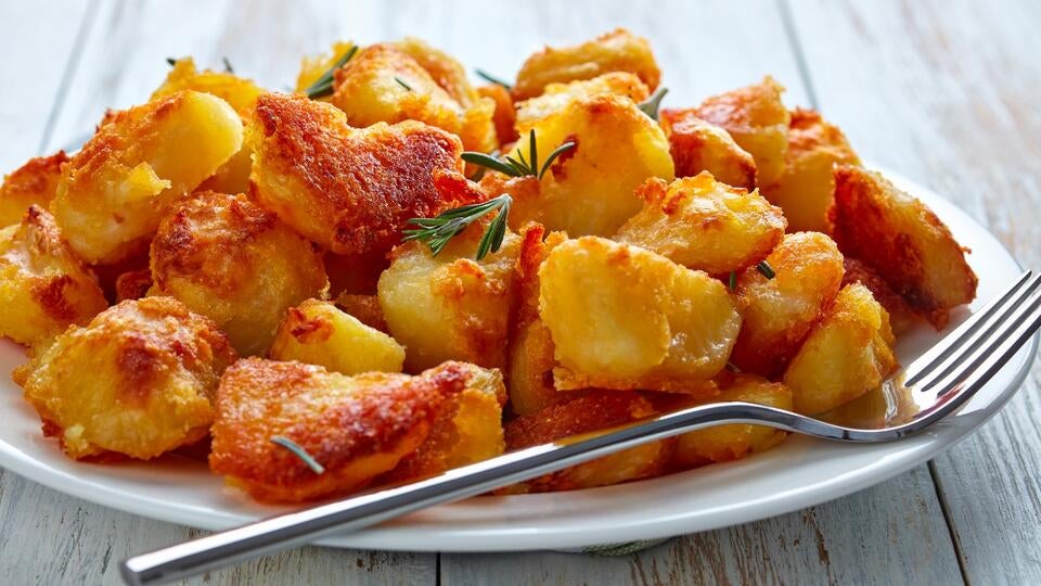 Crispy roast potatoes on a plate with a fork.
