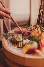 A woman eating sashimi with chopsticks at Yamato.